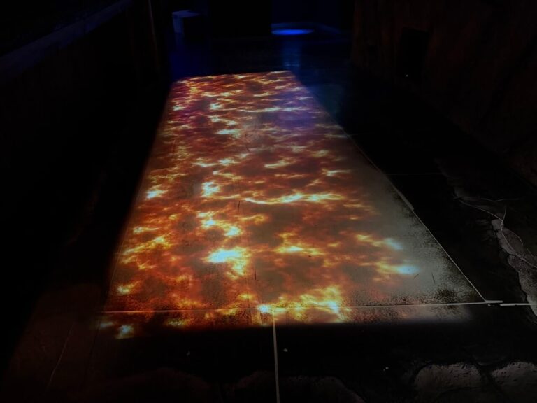 Man sieht eine Projektion von einem Lavastrom auf dem Boden