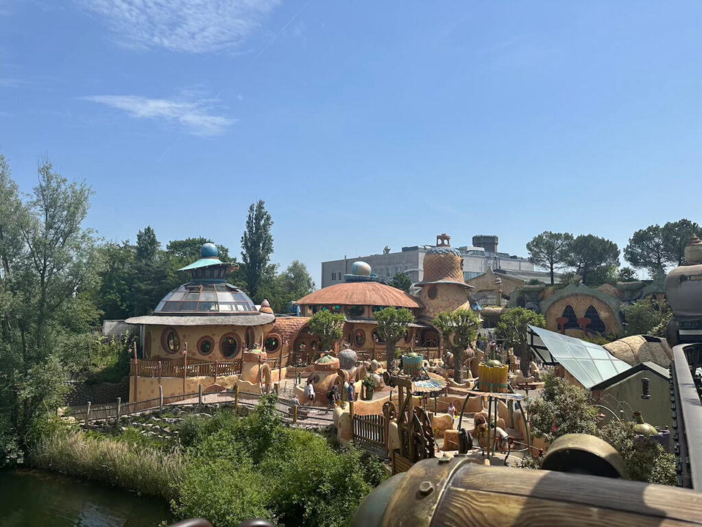 Blick über den farbenfrohen Themenbereich Fantasy/Wuze Town mit runden, organisch geformten Gebäuden im Fantasie-Stil unter blauem Himmel.